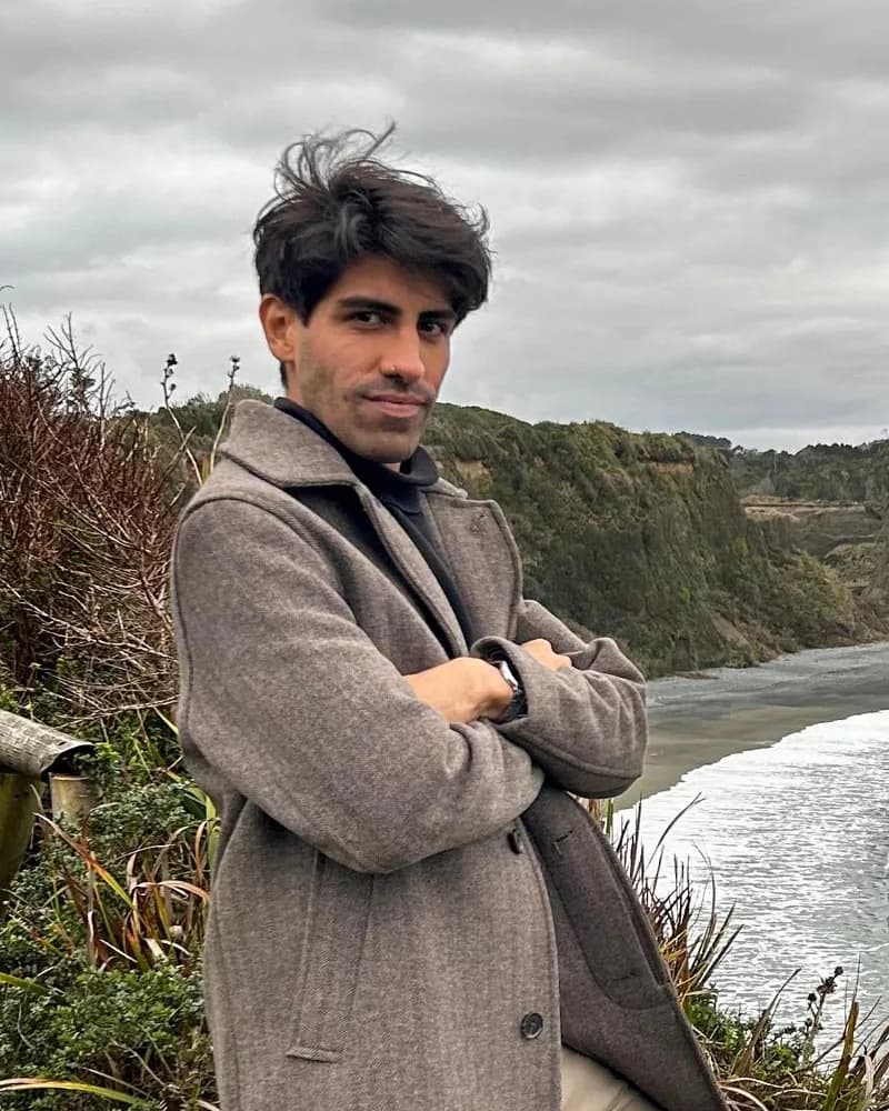 Maximiliano Valdez Aires con un tapado gris y los brazos cruzados, en un mirador sobre la costa.